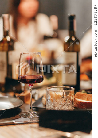 Glass of rich red wine served with cheese plate and fruits on dark wooden background. Appetizers table with wine glasses, rustic style table setting in winery 123873297
