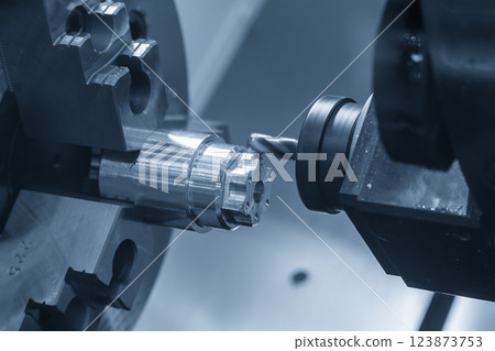 The CNC lathe machine milling cut the metal shaft parts in the light blue scene. 123873753