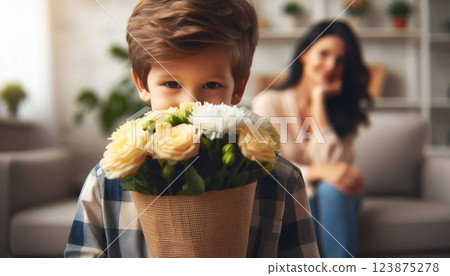 Smiling boy holding bouquet of yellow roses and white flowers as a surprise gift for mother at home. Mother's Day, birthday, or special occasion 123875278