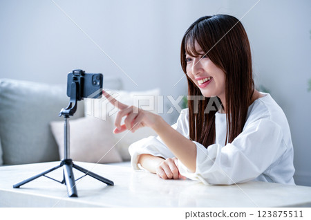 A woman pointing at her smartphone while filming a video 123875511