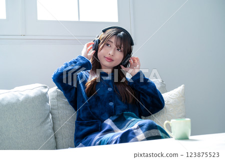 Woman listening to music with headphones in the living room in winter 123875523