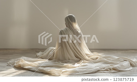 Solitary Figure Draped in a Flowing White Fabric in Soft Sunlight 123875719