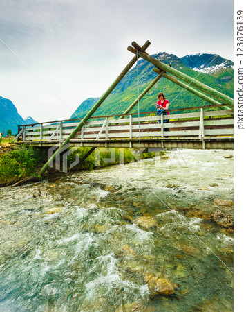 Tourist relaxing on bridge in village Oppstryn Norway Tourist relaxing on bridge in village Oppstryn Norway 123876139