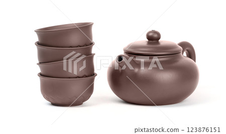 A charming clay teapot sits beside four matching cups stacked neatly. High quality photo A charming clay teapot sits beside four matching cups stacked neatly. High quality photo 123876151