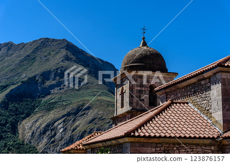 A view of the church tiled roof and bell tower against a backdrop of mountains in Oseja de Sajambre, Spain 123876157
