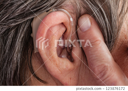 Closeup senior woman using hearing aid 123876172