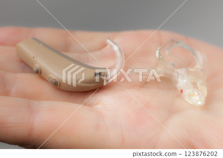 senior person holding hearing aid closeup 123876202