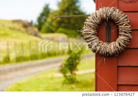 Rounded wicker decoration hanging on wooden wall Rounded wicker decoration hanging on wooden wall 123876427