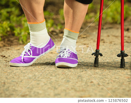 active senior legs in sneakers nordic walking in a park. active senior legs in sneakers nordic walking in a park. 123876502