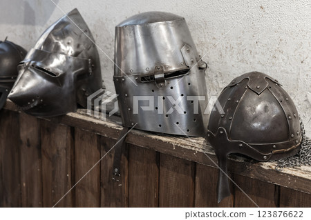 Medieval helmets, crafted from metal and displayed on a wooden shelf. Medieval helmets, crafted from metal and displayed on a wooden shelf. 123876622