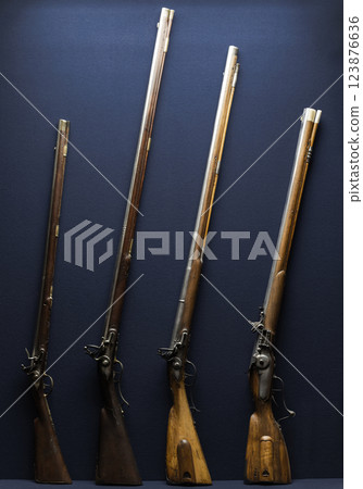 A lineup of antique flintlock rifles, showcasing historical firearm design A lineup of antique flintlock rifles, showcasing historical firearm design 123876636