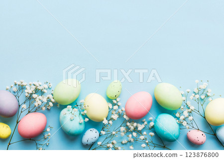 Happy Easter composition. Easter eggs on colored table with gypsophila. Natural dyed colorful eggs background top view with copy space 123876800