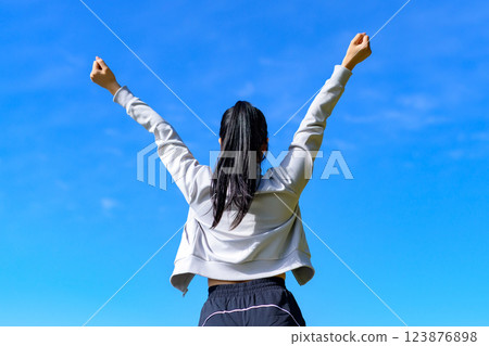 A cool woman with a cool back view posing for the blue sky while walking, stretching, trimming A cool woman with a cool back view posing for the blue sky while walking, stretching, trimming 123876898