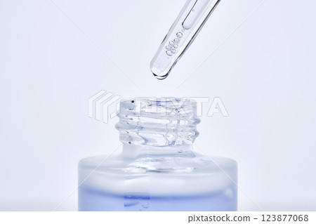 The blue serum drips from the dropper into the bottle. 123877068