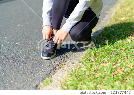 Young woman tying shoelaces while jogging, Untying, Diet, Walking, Walking 123877442