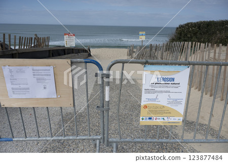 Warning signs indicate coastal erosion at Biscarosse shoreline with restricted access to beach area 123877484