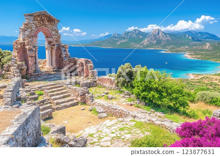Ancient ruins overlook a stunning coastal landscape with blue waters and mountains in the distance 123877631