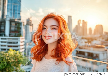 Bright sunset casts a warm glow on a smiling young woman with vibrant red hair in a cityscape Bright sunset casts a warm glow on a smiling young woman with vibrant red hair in a cityscape 123877654