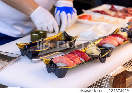 Sushi chef wearing gloves prepares fresh tuna nigiri at a Tokyo seafood market Sushi chef wearing gloves prepares fresh tuna nigiri at a Tokyo seafood market 123878059