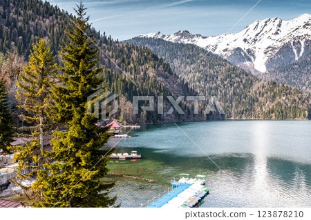 Picturesque lake and high snow capped mountains in the background. Boat station in the foreground 123878210