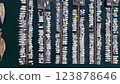 A top-down aerial shot of a marina with rows of neatly docked boats in calm waters. The symmetrical arrangement highlights the variety of vessels and the structured layout of the harbor. 123878646