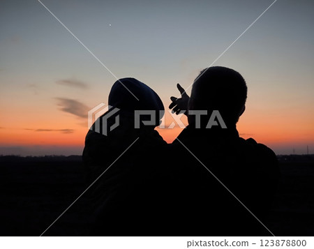 Father care is important kid toddler for healthy family. happy family kid concept. Silhouette at sunset dad and son. With a hand gesture, dad points his son to the first star at sunset in the sky. Father care is important kid toddler for healthy family. happy family kid concept. Silhouette at sunset dad and son. With a hand gesture, dad points his son to the first star at sunset in the sky. 123878800