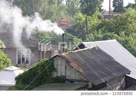 Smoke comes from the chimney of a village house, a bathhouse, garden houses, a summer cottage Smoke comes from the chimney of a village house, a bathhouse, garden houses, a summer cottage 123878892