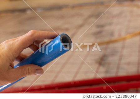 Hand holding blue pipe of the water supply and heating system. Closeup. Hand holding blue pipe of the water supply and heating system. Closeup. 123880347
