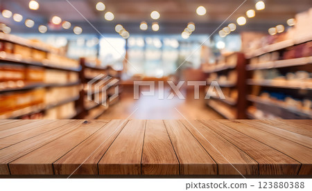 Wooden table in the foreground with blurred supermarket aisles filled with various products in the background, creating a vibrant and busy shopping environment 123880388