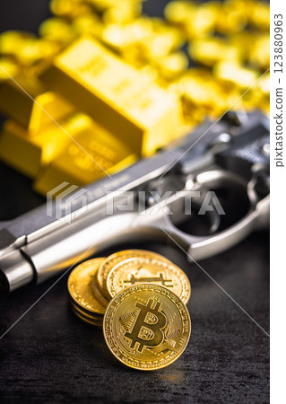 Bitcoin and gun. Gold coin cryptocurrency and gold bars on black table. 123880963