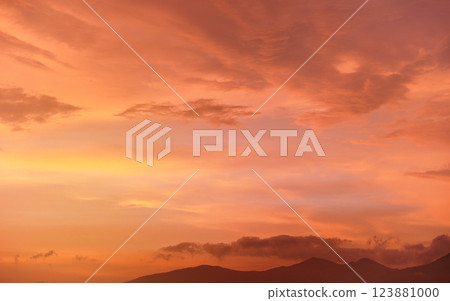Calm orange and pink sunset sky, silhouettes of mountains below - can be used as background with subjects placed in front 123881000