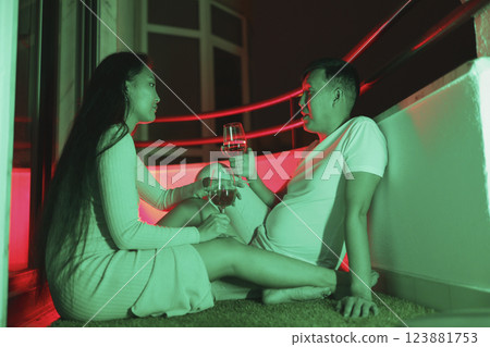 Couple drinking wine on balcony at night with neon lights Couple drinking wine on balcony at night with neon lights 123881753
