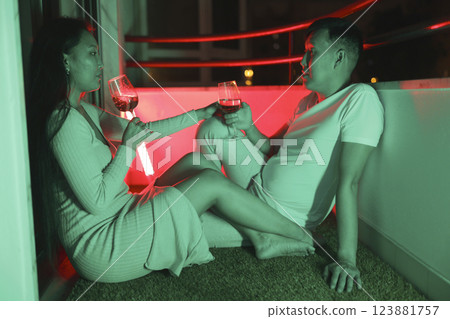Young couple drinking wine on balcony at night with neon lights 123881757