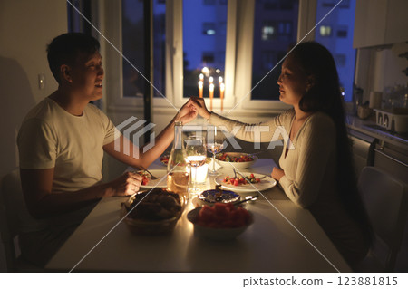 Young couple holding hands while having romantic dinner at home Young couple holding hands while having romantic dinner at home 123881815