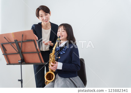 一位吹奏薩克斯風的銅管樂隊成員和一位女老師 123882341