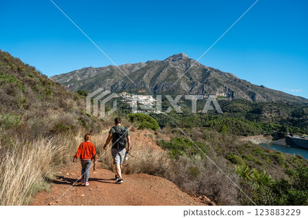 Father and daughter hiking on mountain trail with scenic view Father and daughter hiking on mountain trail with scenic view 123883229