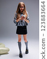 A Trendy Young Girl with Phone, Impressively Showcasing Modern Fashion Styles and Trends 123883664
