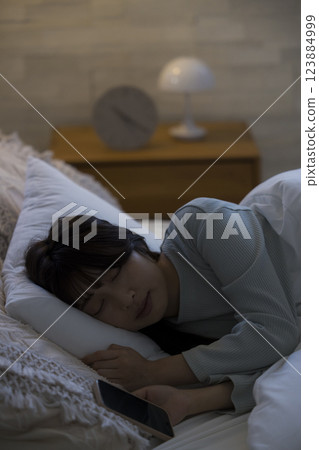 一名婦女在床上的看一個智能手機 123884999