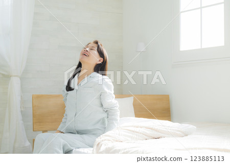 躺在床上伸展身體的老年婦女 躺在床上伸展身體的老年婦女 123885113