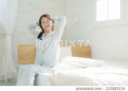 躺在床上伸展身體的老年婦女 躺在床上伸展身體的老年婦女 123885114