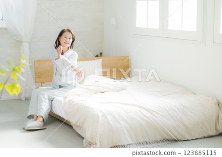 躺在床上伸展身體的老年婦女 躺在床上伸展身體的老年婦女 123885115