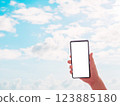 Hand holding a smartphone against the blue sky 123885180