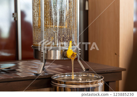Fresh pure honey flowing out of the centrifuge 123885230