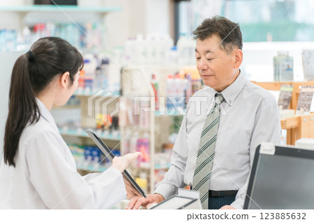 Seniors and female pharmacists receiving instructions using a tablet PC at a pharmacy (receipt computer) 123885632