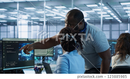 Manager coming to technician desk to give instructions on doing maintenance on artificial intelligence neural networks. Supervisor overseeing worker using AI system software, camera A Manager coming to technician desk to give instructions on doing maintenance on artificial intelligence neural networks. Supervisor overseeing worker using AI system software, camera A 123885985