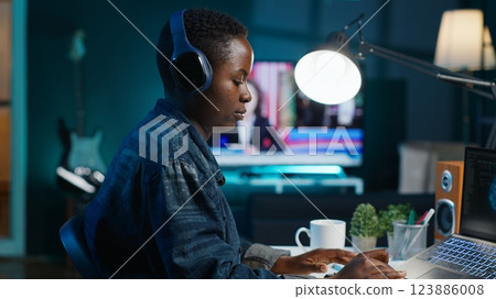 Programmer in living room office typing on keyboard, updating artificial intelligence neural networks, writing binary code scripts. Freelancing system administrator upgrading high tech AI, camera A 123886008