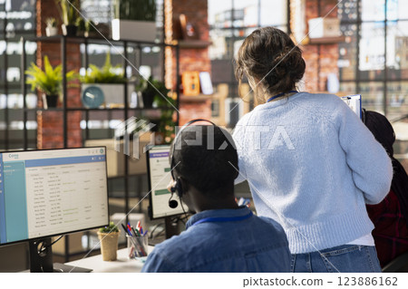 Customer service manager supervising agents logging customer interactions in CSM system. Call center supervisor overseeing workers using customer service management software 123886162