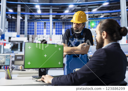 Photovoltaics factory engineering team using green screen PC to improve solar panels assembly processes. Coworkers use chroma key computer to calibrate equipment for precise solar cells manufacturing Photovoltaics factory engineering team using green screen PC to improve solar panels assembly processes. Coworkers use chroma key computer to calibrate equipment for precise solar cells manufacturing 123886209