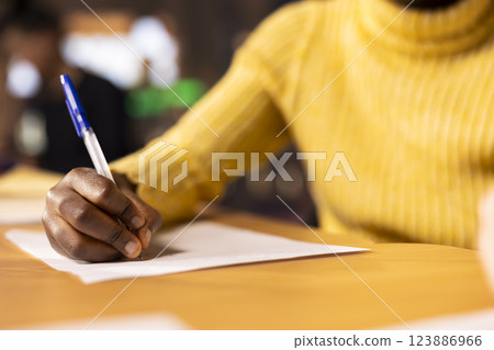 African american teen solving the school assignment for literature class lesson, writing descriptive or narrative ideas for a new essay. Girl preparing with research done for the course. Close up. 123886966