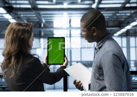 Data center admins using isolated screen tablet to calibrate energy usage. Server hub workers using chroma key device to inspect UPS configurations, doing maintenance on equipment Data center admins using isolated screen tablet to calibrate energy usage. Server hub workers using chroma key device to inspect UPS configurations, doing maintenance on equipment 123887016